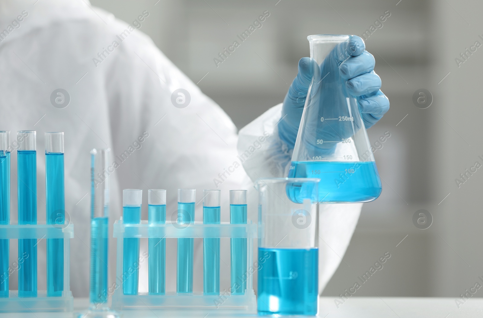 Photo of Scientist holding flask with sample in laboratory, closeup
