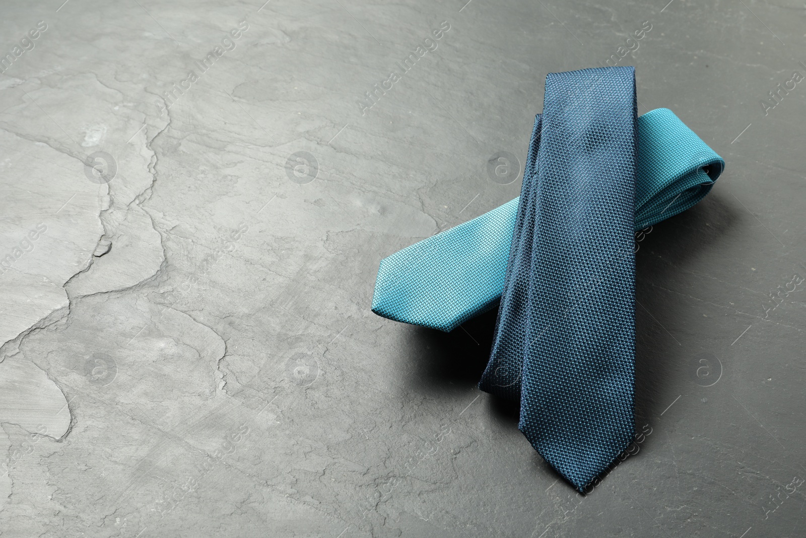 Photo of Two neckties on grey textured background, above view. Space for text