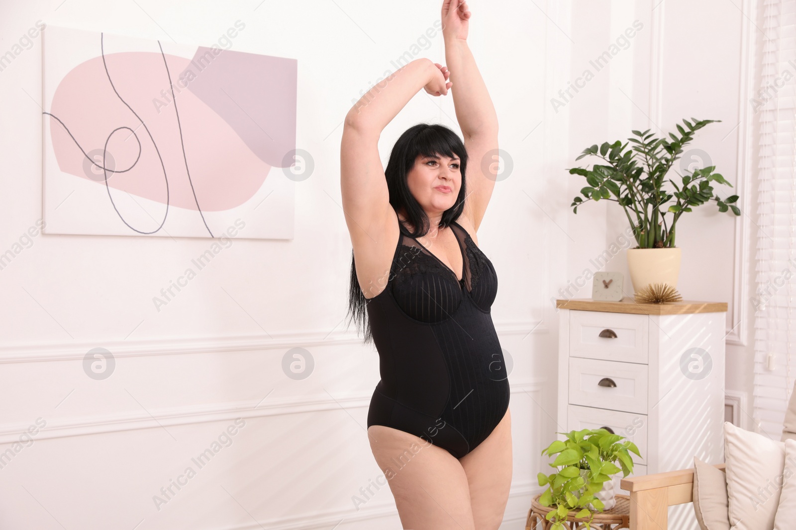 Photo of Beautiful overweight woman in black underwear dancing at home. Plus-size model