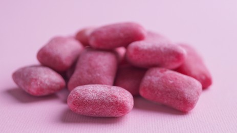 Photo of Heap of tasty sweet chewing gums on pink background, closeup