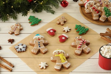 Photo of Making homemade Christmas cookies. Gingerbread people and festive decor on white wooden table