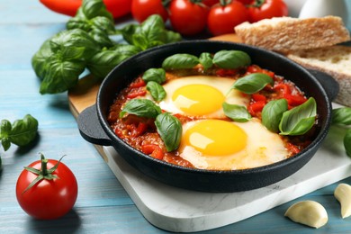 Delicious Shakshuka served on light blue wooden table, closeup