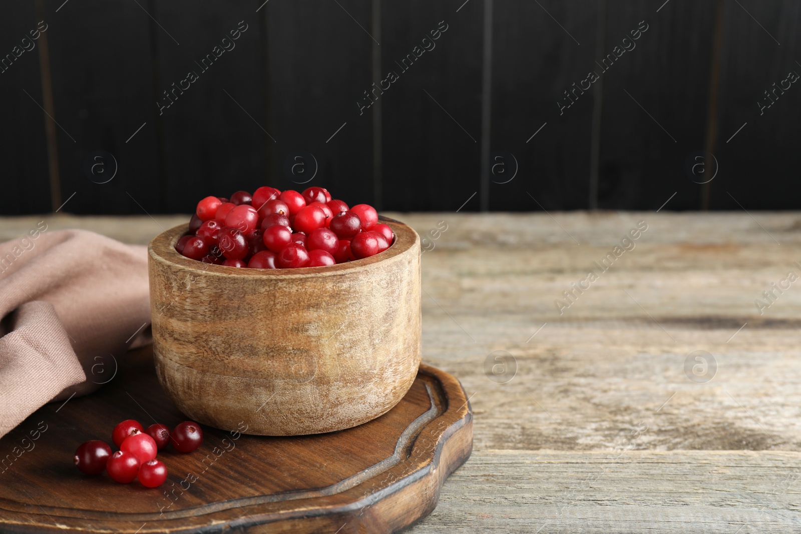 Photo of Cranberries in bowl on wooden table, space for text