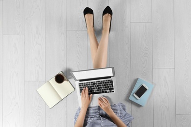 Photo of Top view of woman with laptop sitting on floor, closeup. Mockup for design