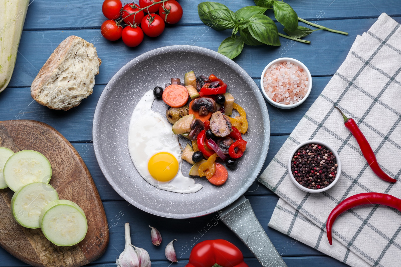 Photo of Flat lay composition with delicious cooked egg and vegetables in frying pan on blue table