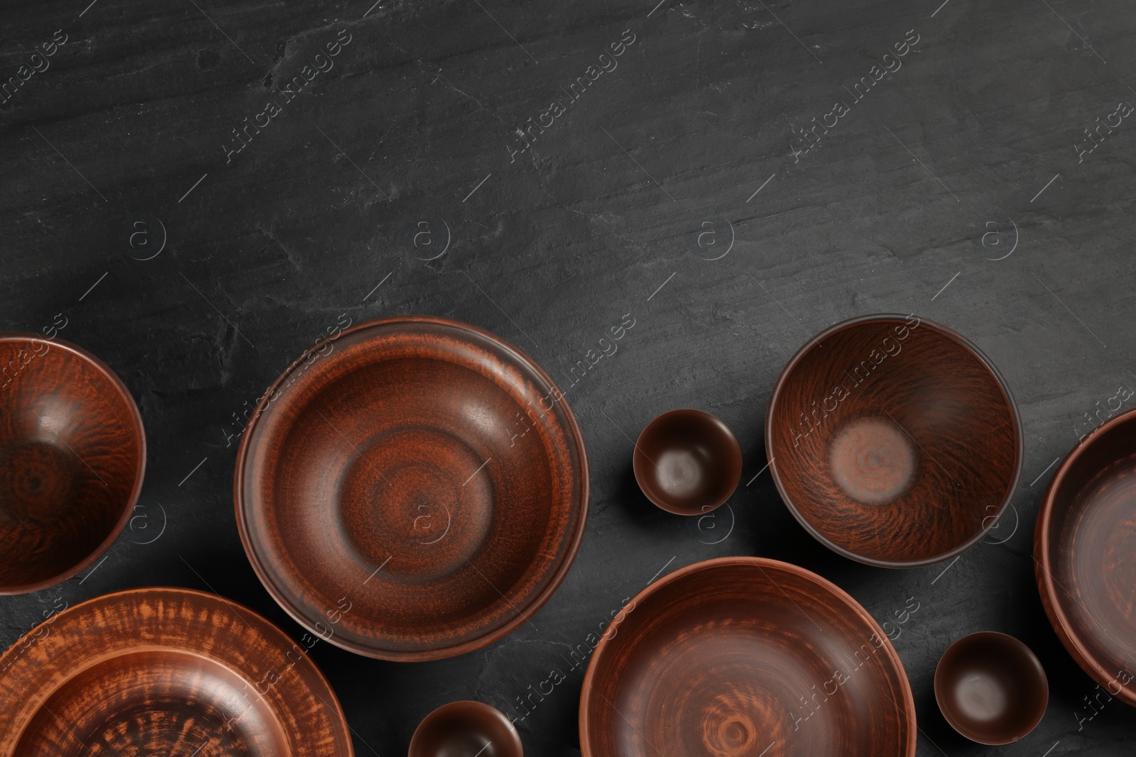 Photo of Set of clay utensils on black table, flat lay. Space for text