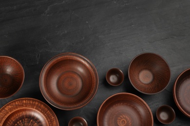 Photo of Set of clay utensils on black table, flat lay. Space for text