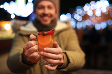 Happy man with mulled wine at winter fair, focus on hands