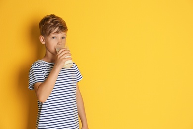 Adorable little boy with glass of milk on color background