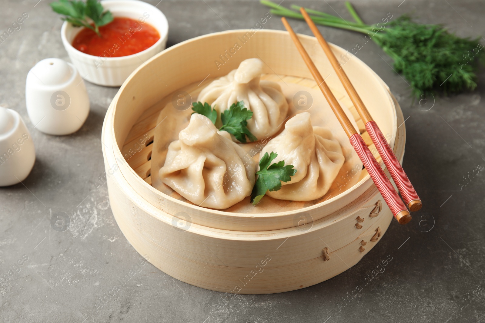 Photo of Bamboo steamer with tasty baozi dumplings and chopsticks on table