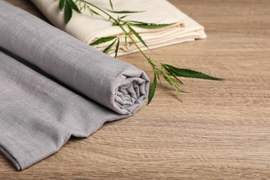 Photo of Hemp cloths and green branch on wooden table