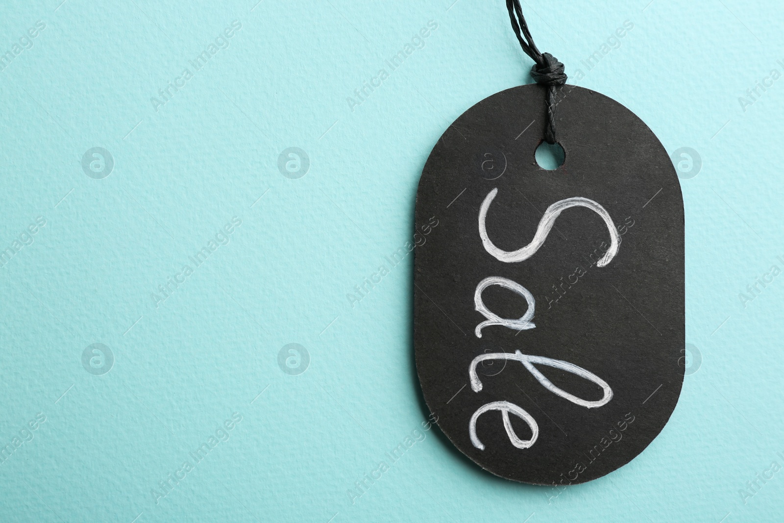 Photo of Top view of tag with word SALE on turquoise background, space for text. Black Friday concept