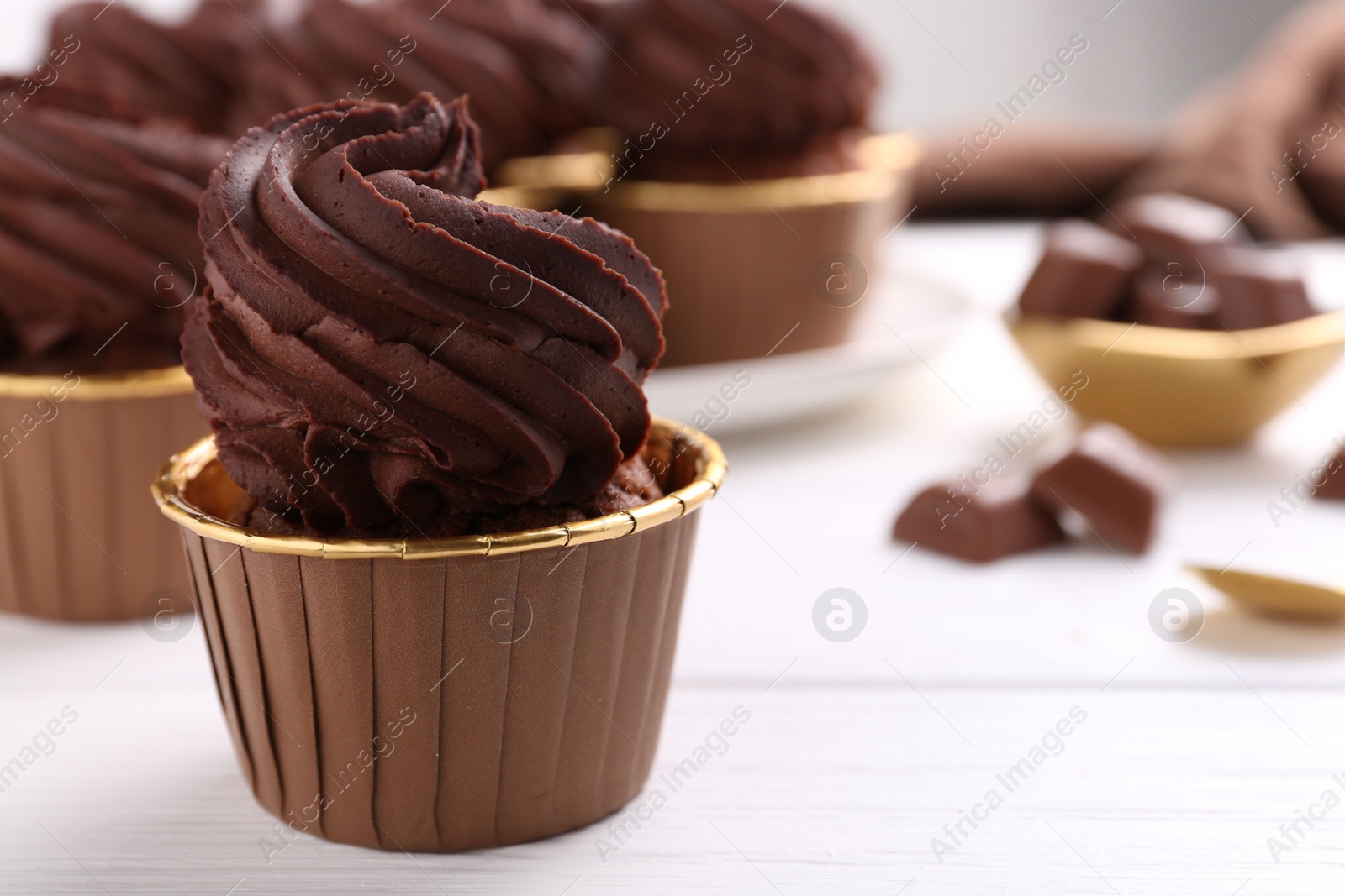 Photo of Delicious chocolate cupcake on white wooden table, closeup. Space for text