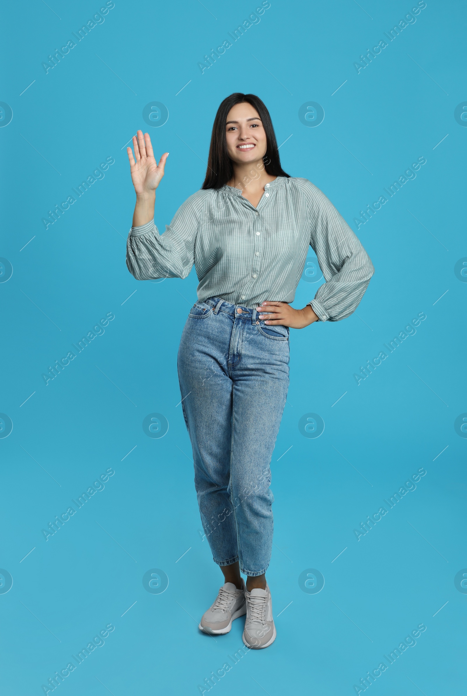 Photo of Happy woman waving to say hello on light blue background