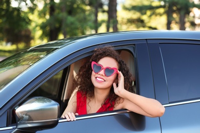 Photo of Young beautiful African-American woman wearing heart shaped glasses in car