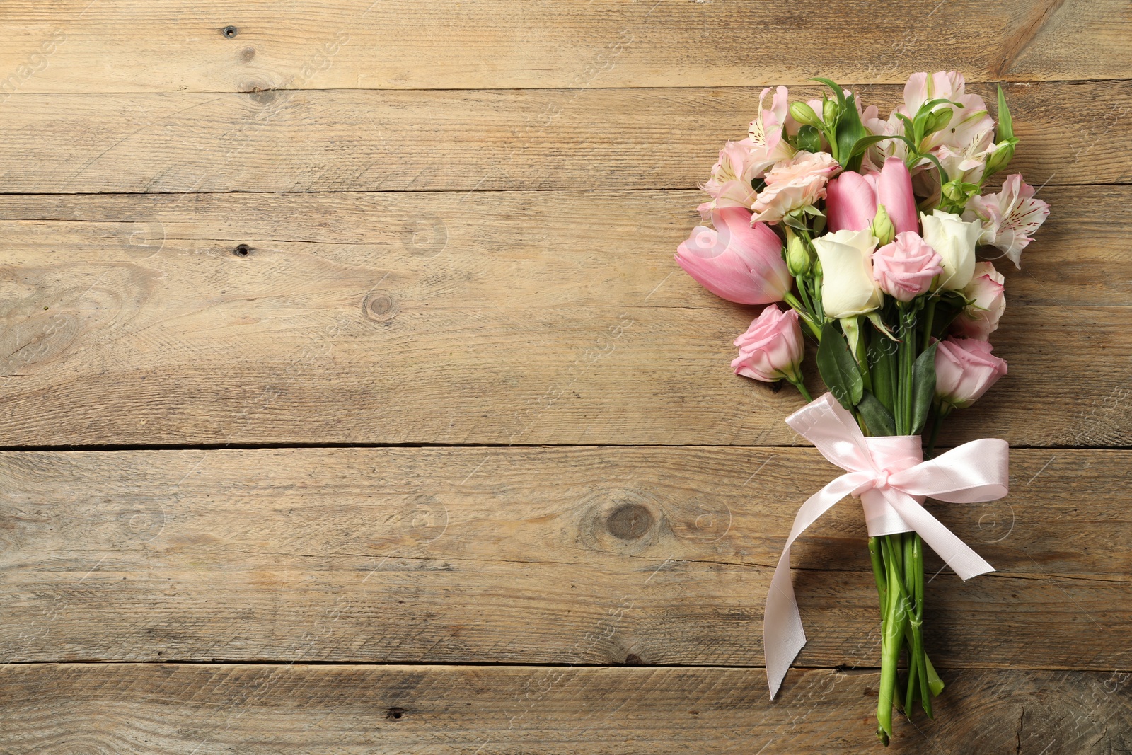 Photo of Happy Mother's Day. Bouquet of beautiful flowers tied with pink ribbon on wooden table, top view. Space for text