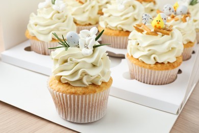 Tasty Easter cupcakes in box on wooden table, closeup