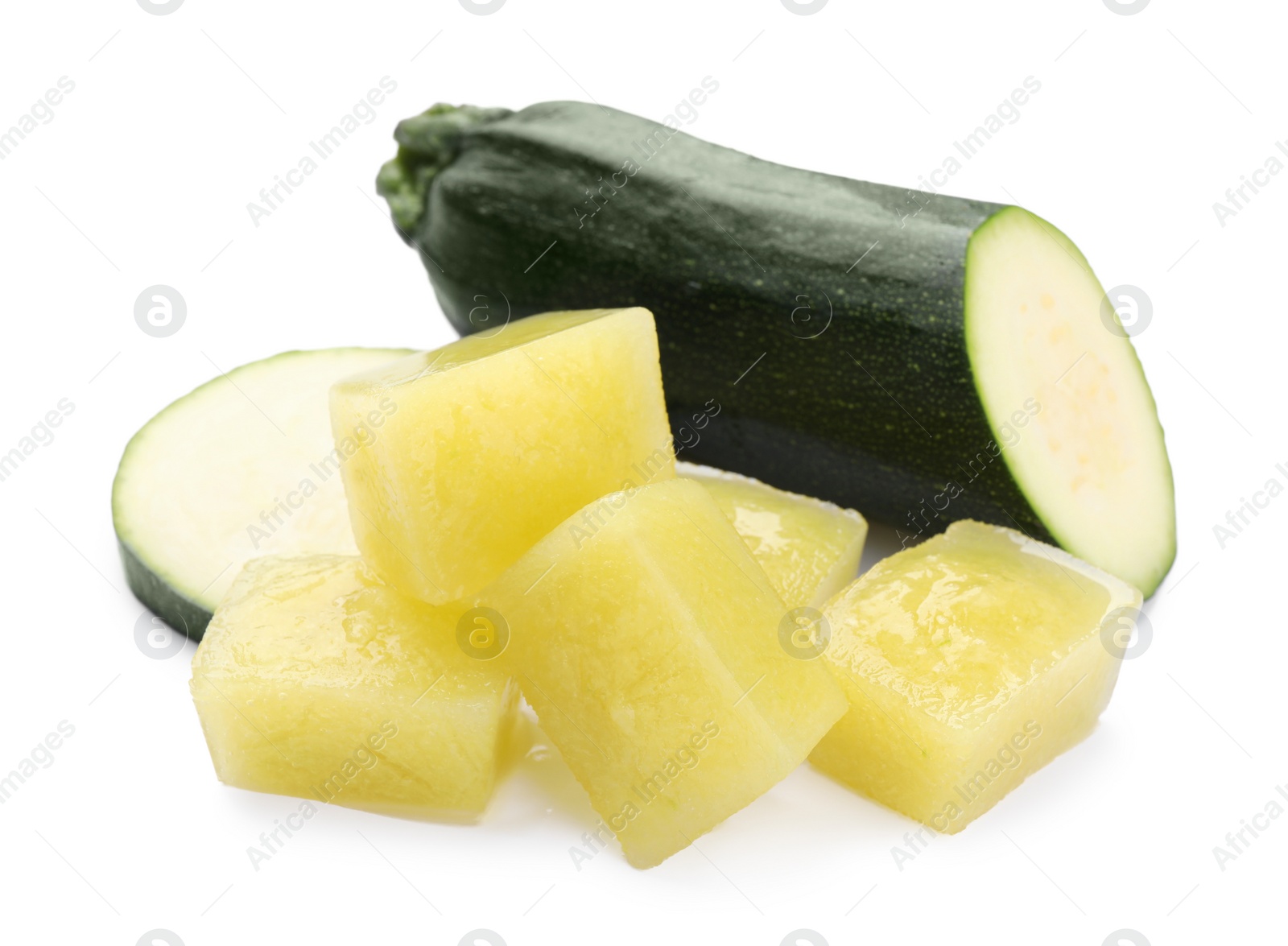 Photo of Frozen zucchini puree cubes and fresh zucchini isolated on white