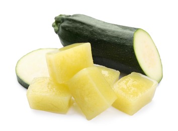 Photo of Frozen zucchini puree cubes and fresh zucchini isolated on white