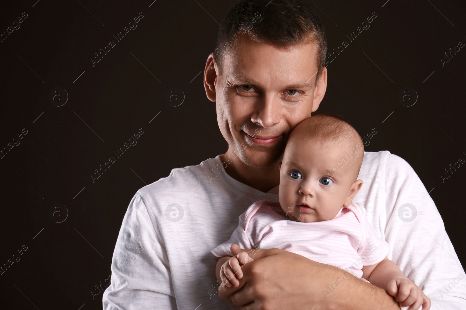 Photo of Happy father with his little baby on dark background