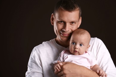 Photo of Happy father with his little baby on dark background