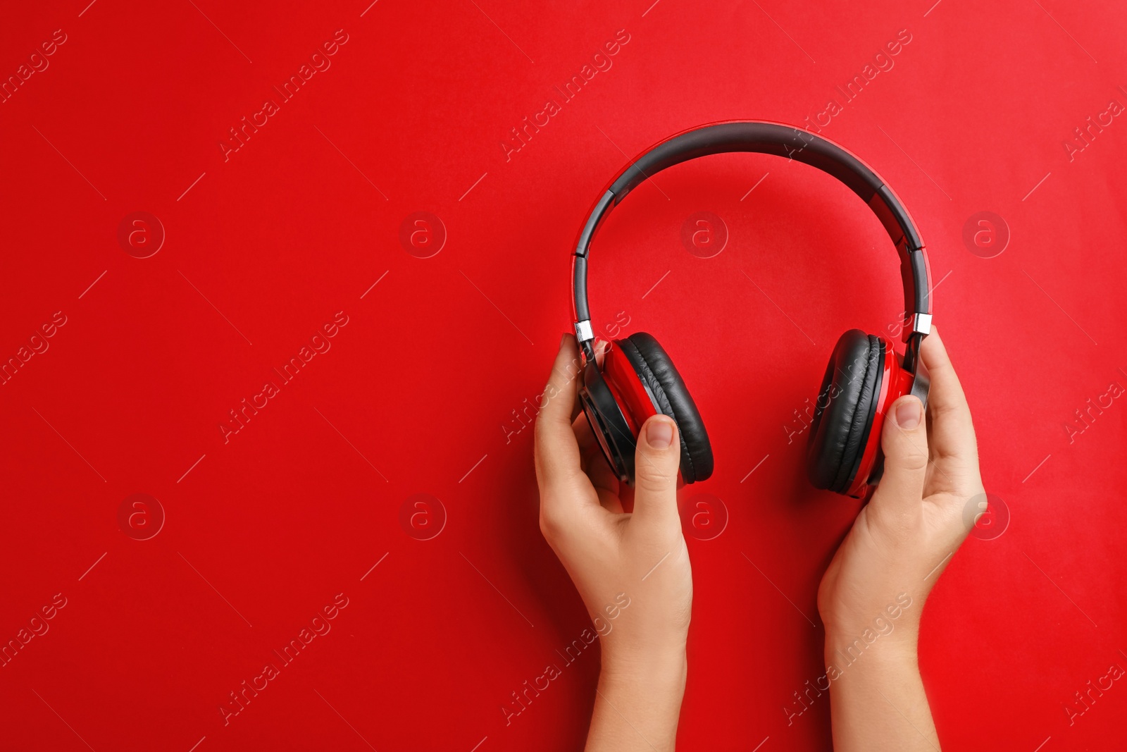 Photo of Woman holding headphones on color background, top view. Space for text