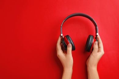 Woman holding headphones on color background, top view. Space for text