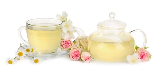 Aromatic herbal tea in glass cup, teapot and flowers isolated on white