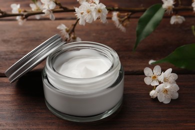 Photo of Jar of face cream and flowers on wooden table