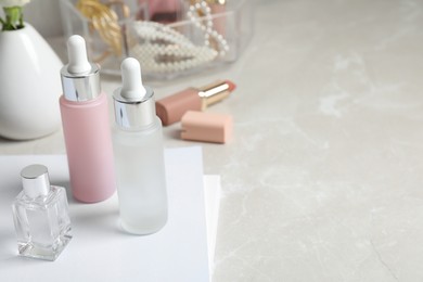 Bottles of cosmetic products on light grey table, space for text