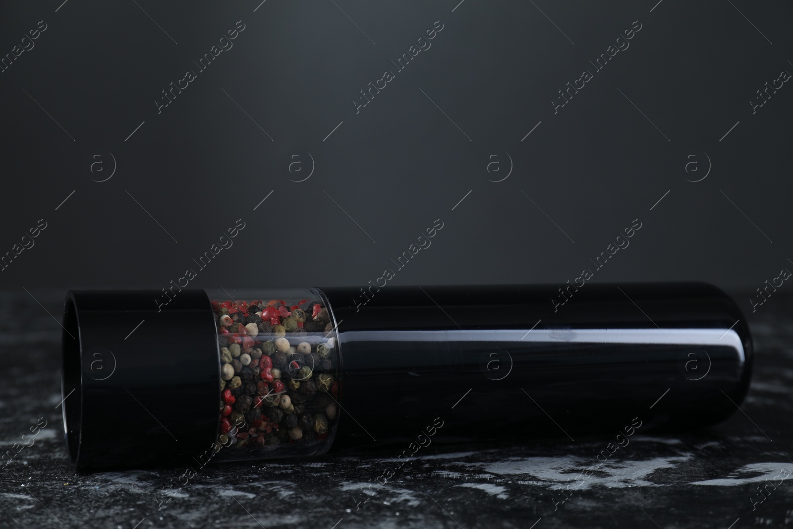 Photo of Pepper shaker on dark marble table, closeup