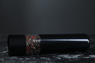 Photo of Pepper shaker on dark marble table, closeup