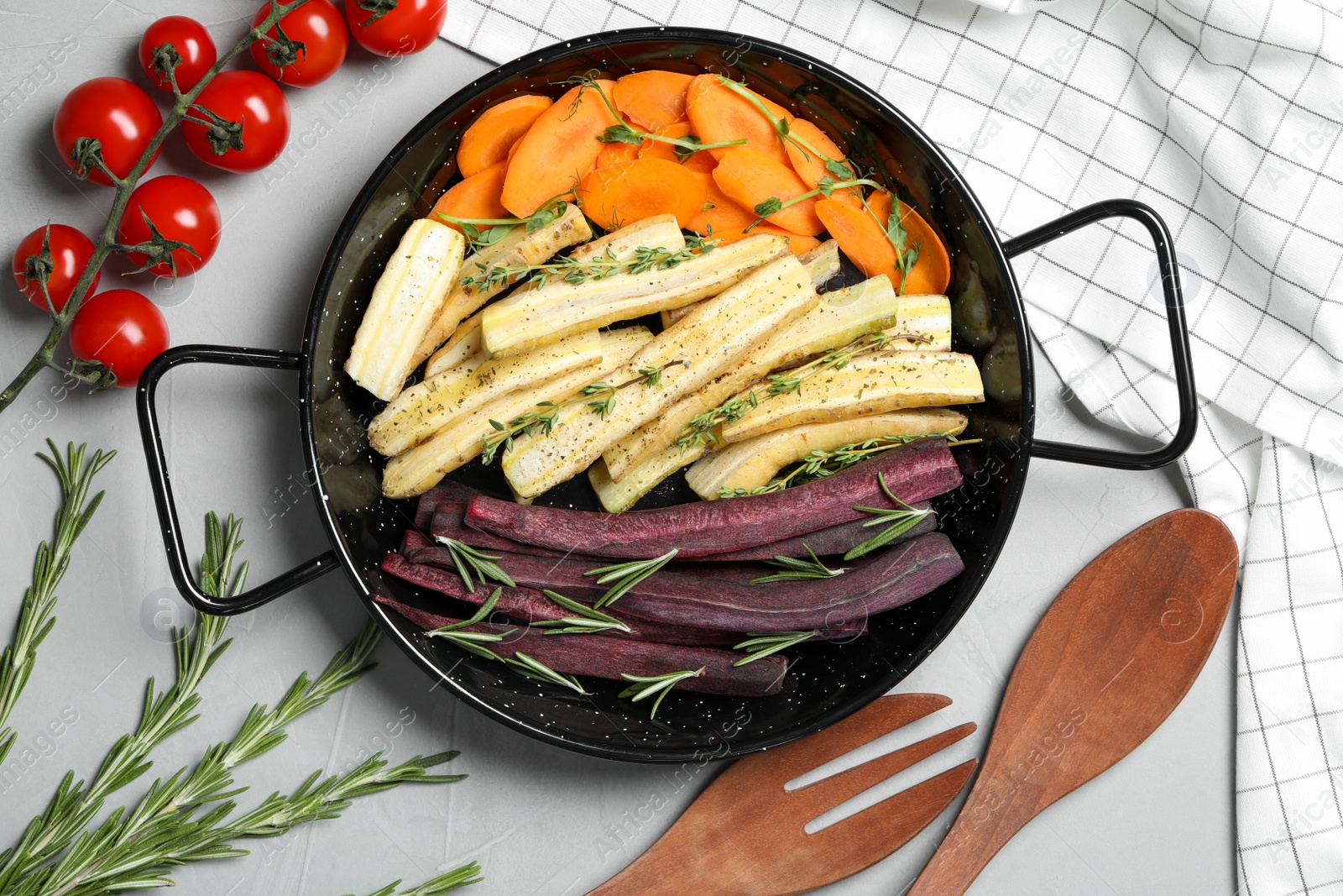 Photo of Flat lay composition with raw cut carrots in frying pan on light grey table