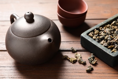 Clay teapot and Tie Guan Yin oolong dry leaves on wooden table