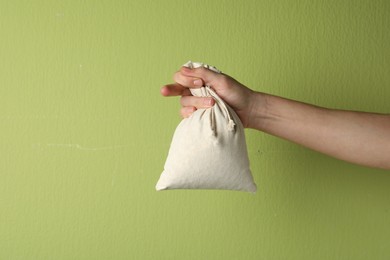 Photo of Woman holding full cotton eco bag on light green background, closeup
