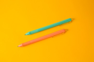 Photo of Two erasable pens on yellow background, flat lay