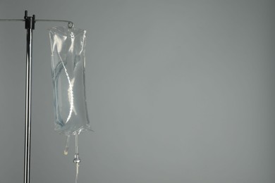 Photo of IV infusion set on pole against grey background. Space for text