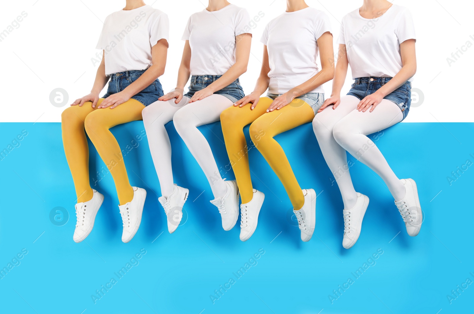 Photo of Group of women wearing colorful tights and stylish shoes sitting on color background, closeup