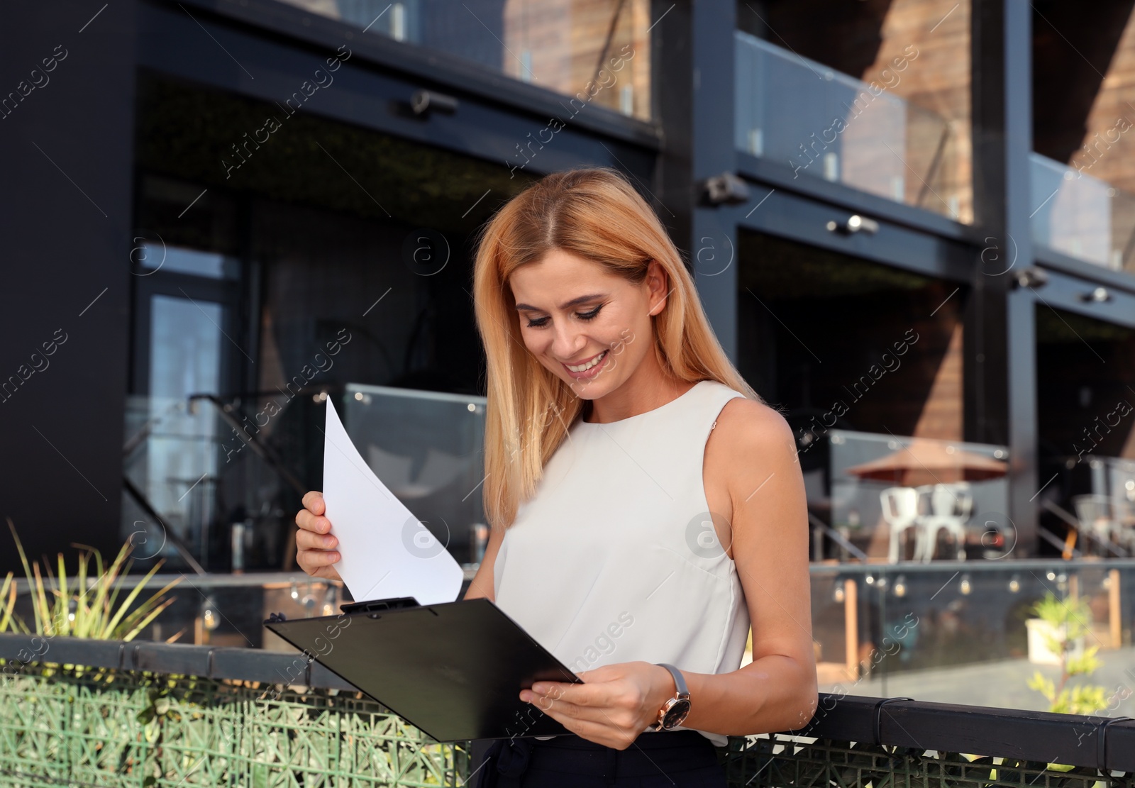 Photo of Female real estate agent with clipboard outdoors