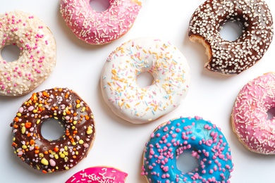 Photo of Delicious doughnuts with sprinkles on light background, top view