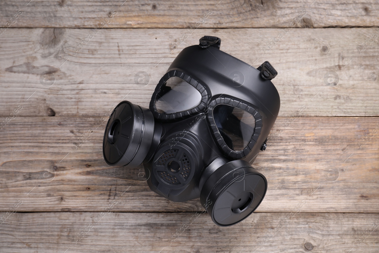 Photo of One gas mask on wooden background, top view