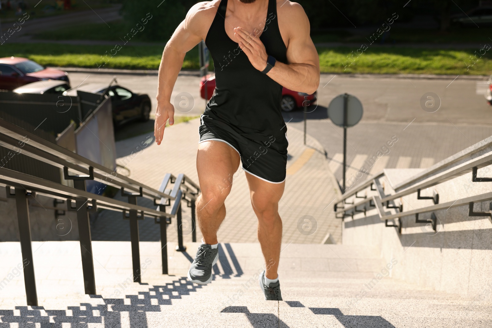 Photo of Man running up stairs outdoors on sunny day, closeup