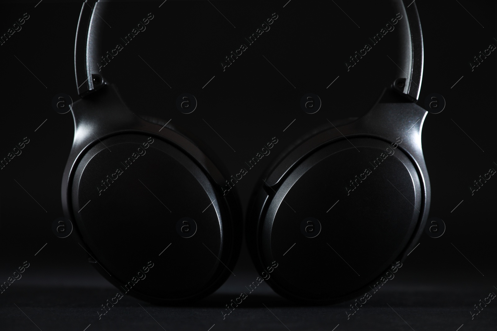 Photo of Modern wireless headphones on black background, closeup