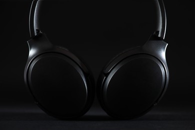 Photo of Modern wireless headphones on black background, closeup