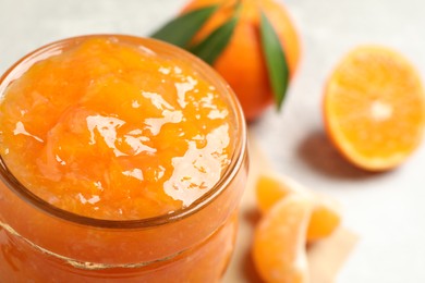 Delicious tangerine jam in glass jar, closeup