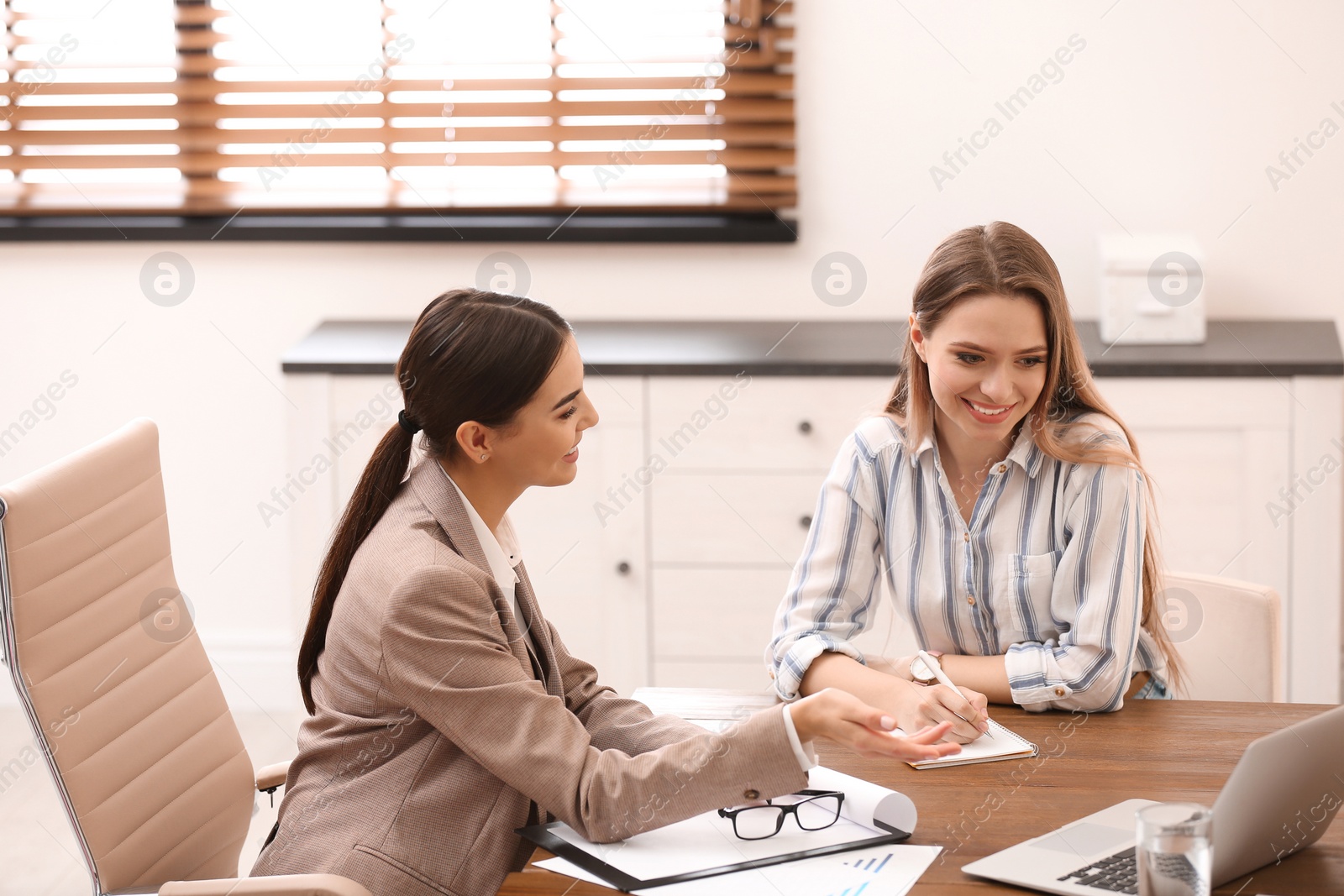 Photo of Female insurance agent consulting young woman in office