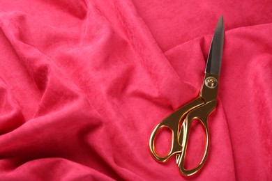 Scissors on pink crumpled fabric. Space for text