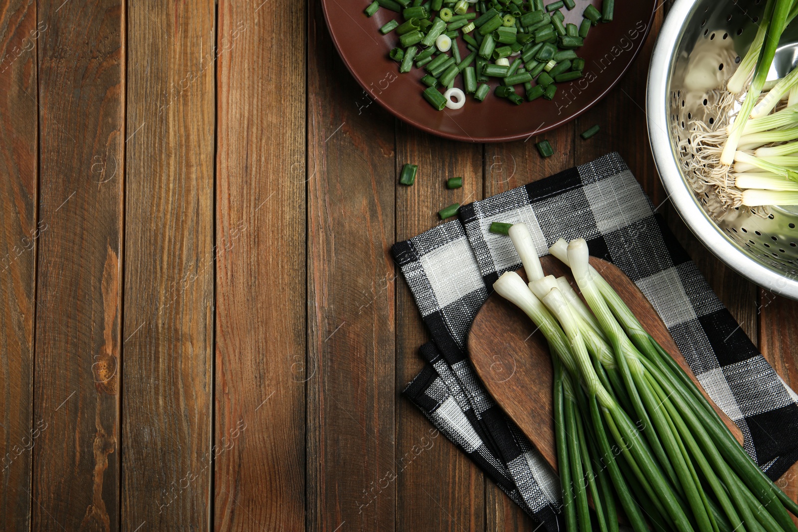 Photo of Fresh green spring onions on wooden table, flat lay. Space for text