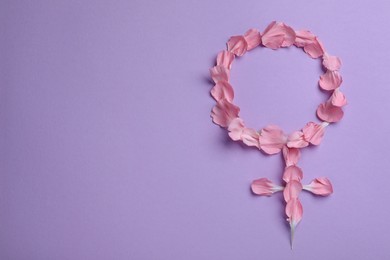 Photo of Female gender sign made of petals on violet background, top view and space for text. Women's health concept