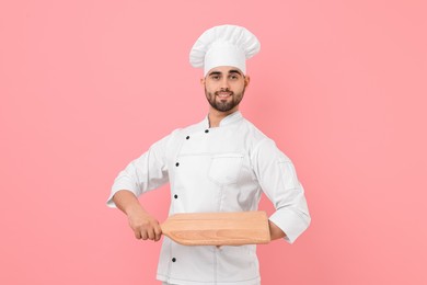 Photo of Professional chef with serving board on pink background